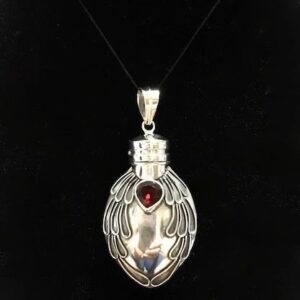 A silver necklace with a bottle of liquid and a red stone.