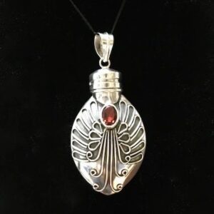 A silver pendant with a red stone on it.