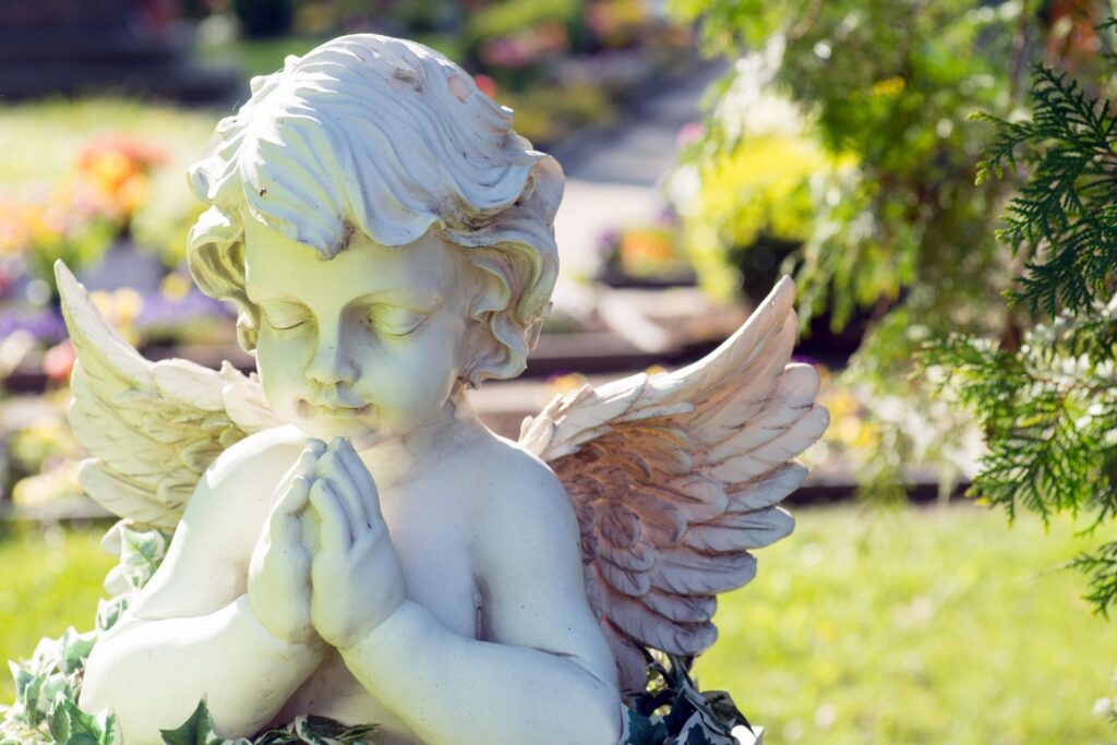 A statue of an angel with hands folded in prayer.